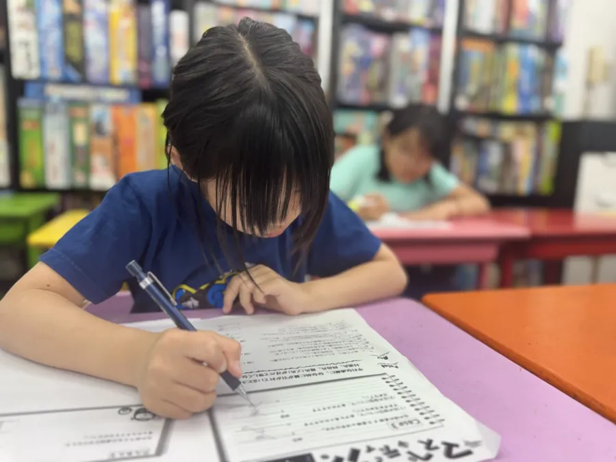 鉛筆を持ち、算数の教材に図を書き込みながら考える女の子