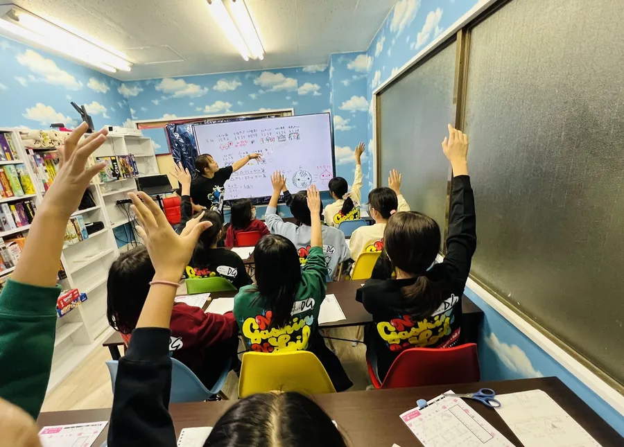 教室全体で手を挙げながら授業に参加する生徒たち