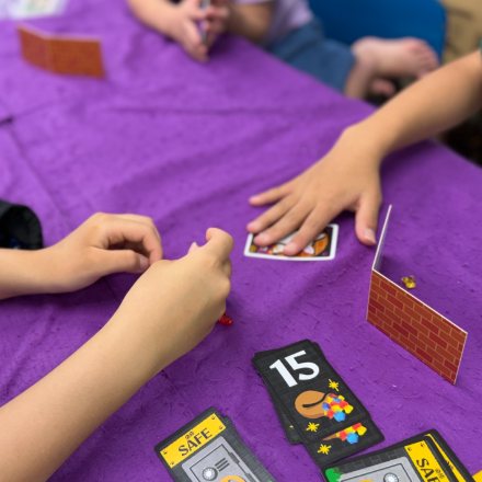 ボードゲームのカードと駒を囲む子どもたちの手元