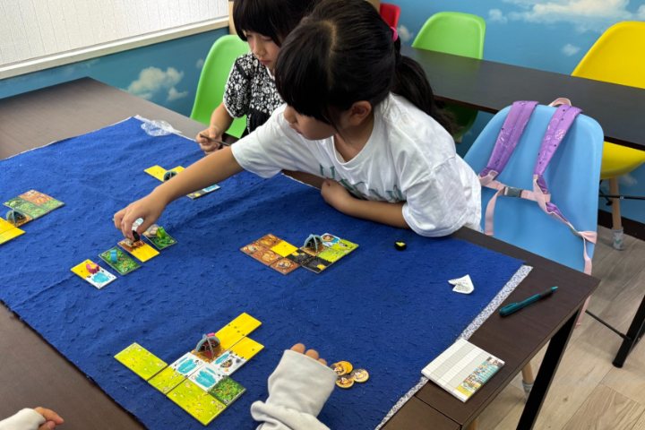 盤面の駒を動かして作戦を試す女子児童